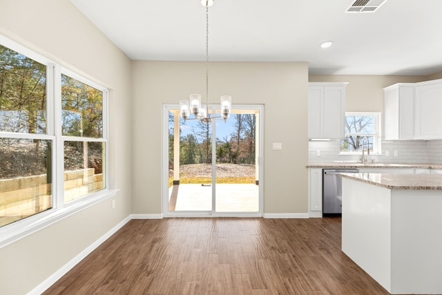 kitchen featuring decorative backsplash, white cabinets, decorative light fixtures, an inviting chandelier, and dishwasher