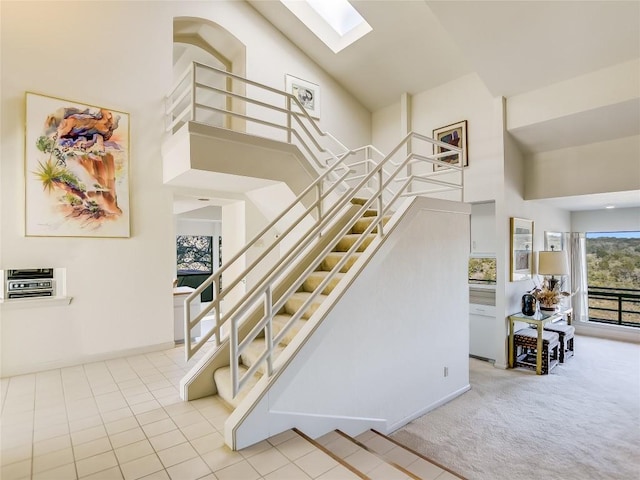 stairs featuring carpet flooring, a skylight, and high vaulted ceiling