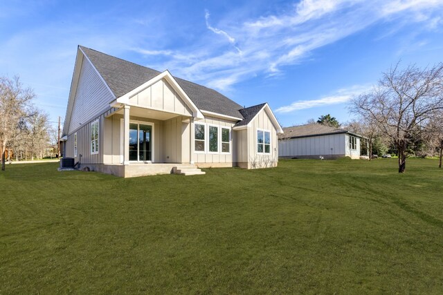 rear view of house featuring cooling unit and a lawn