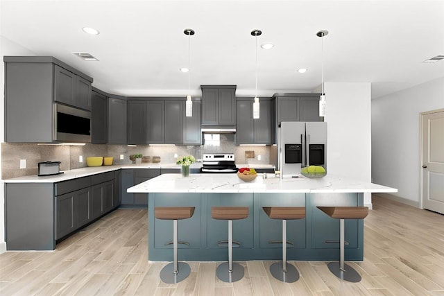 kitchen featuring gray cabinets, a center island with sink, and appliances with stainless steel finishes