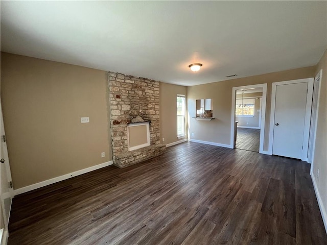 unfurnished living room with dark hardwood / wood-style flooring and a stone fireplace