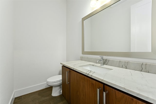 bathroom with toilet, vanity, and hardwood / wood-style flooring