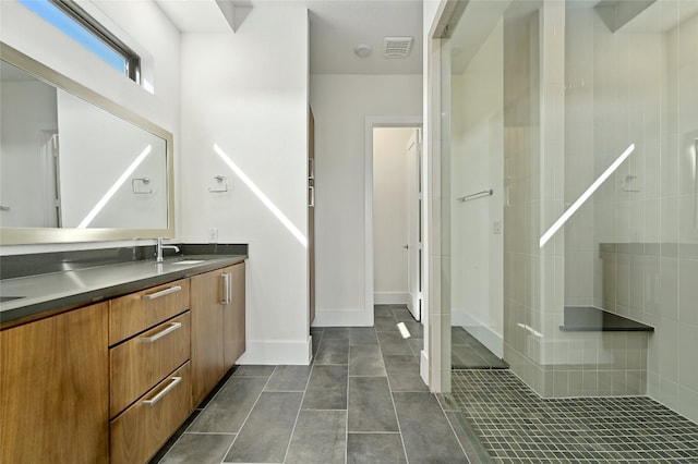 bathroom featuring a tile shower, tile patterned floors, and vanity