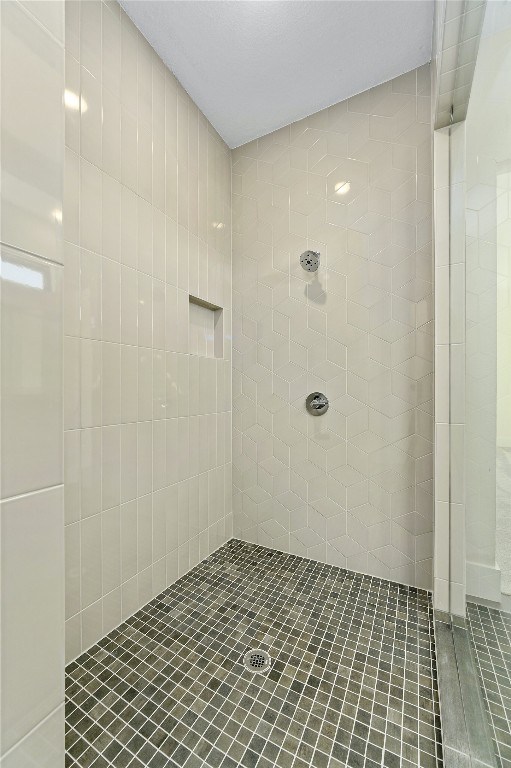 bathroom with tiled shower and tile patterned flooring