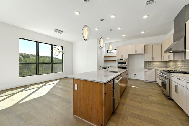 kitchen featuring appliances with stainless steel finishes, light wood-type flooring, backsplash, sink, and light stone counters