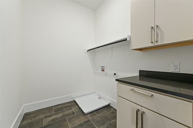 laundry room featuring electric dryer hookup, hookup for a washing machine, dark tile patterned floors, and cabinets