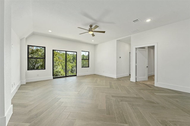 empty room with ceiling fan, a wealth of natural light, and light parquet floors