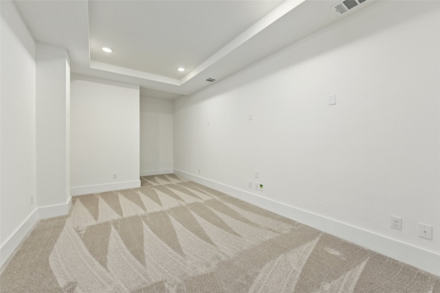 carpeted empty room with a raised ceiling