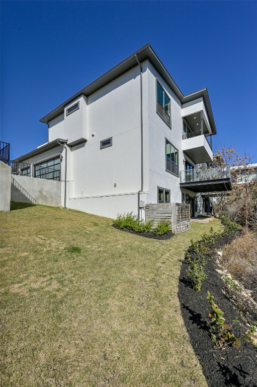 view of home's exterior with a balcony and a yard