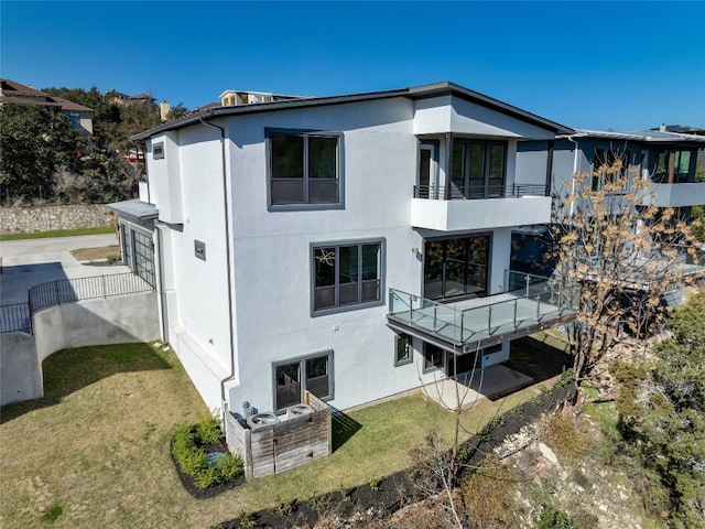 back of house with a lawn and a balcony