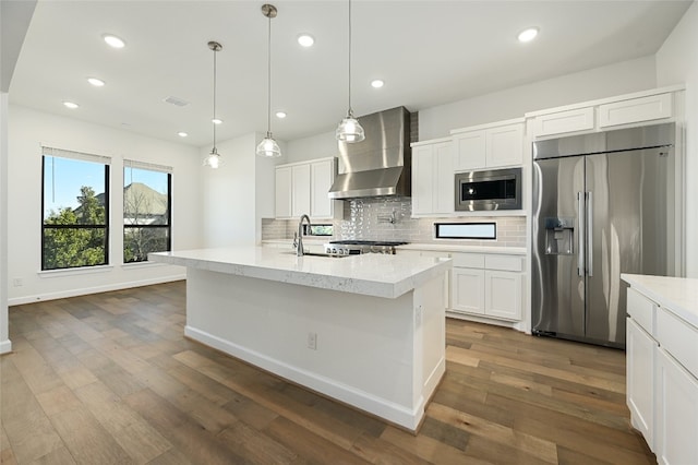 kitchen with white cabinetry, built in appliances, wall chimney range hood, backsplash, and dark hardwood / wood-style flooring