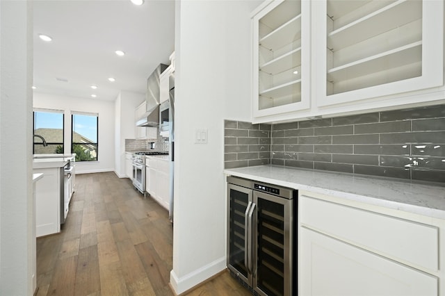 kitchen featuring light stone countertops, white cabinets, dark hardwood / wood-style flooring, stainless steel range, and wine cooler