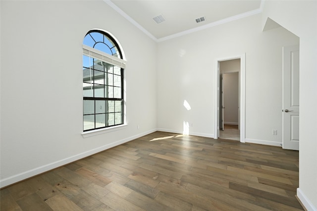 empty room featuring wood-type flooring, lofted ceiling, and crown molding