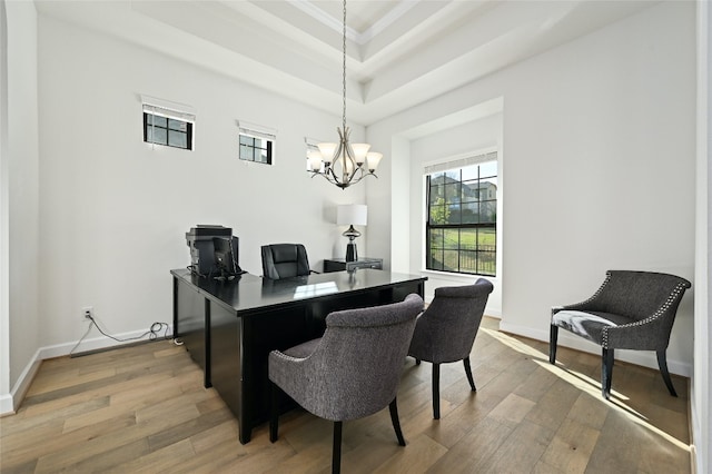 home office with a notable chandelier, a high ceiling, hardwood / wood-style flooring, and a raised ceiling