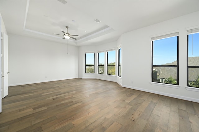 empty room featuring hardwood / wood-style floors, a tray ceiling, and ceiling fan