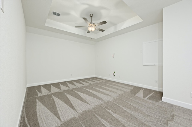 carpeted spare room featuring ceiling fan and a raised ceiling