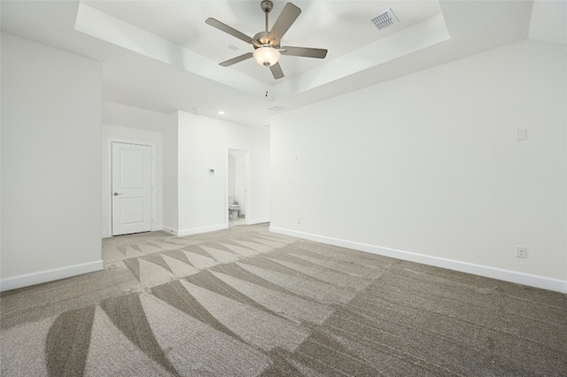 carpeted spare room featuring a tray ceiling and ceiling fan