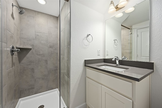 bathroom featuring tiled shower and vanity