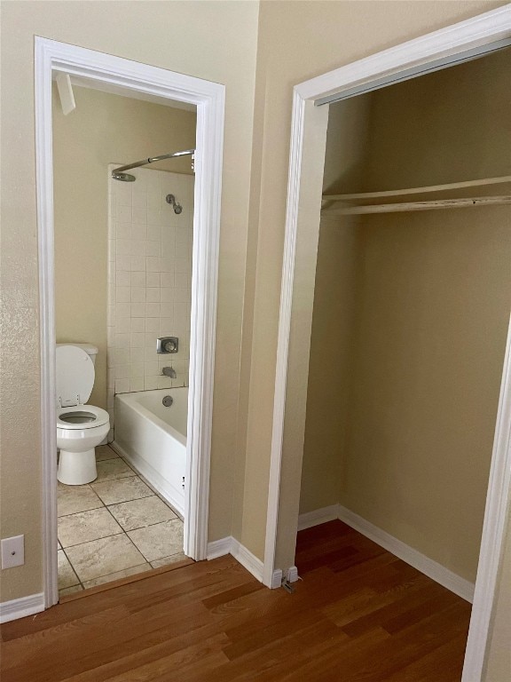 bathroom featuring toilet, tiled shower / bath, and hardwood / wood-style flooring