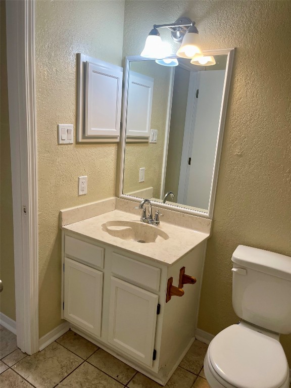 bathroom with a notable chandelier, toilet, vanity, and tile flooring