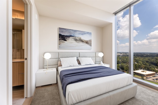 bedroom with multiple windows, light wood-type flooring, and expansive windows