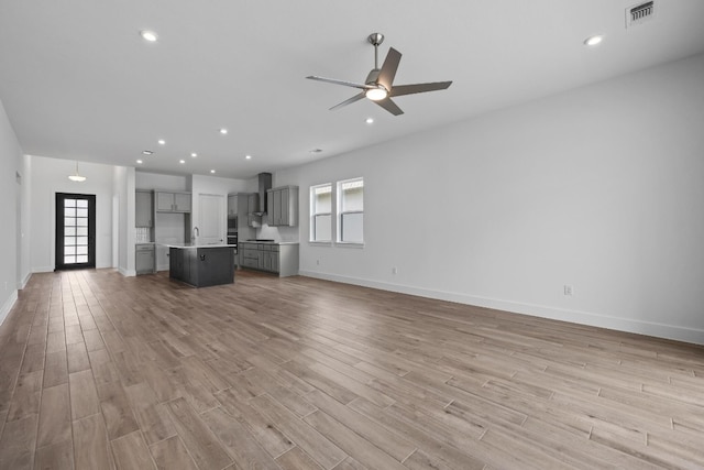 unfurnished living room with light wood-type flooring, ceiling fan, and a healthy amount of sunlight