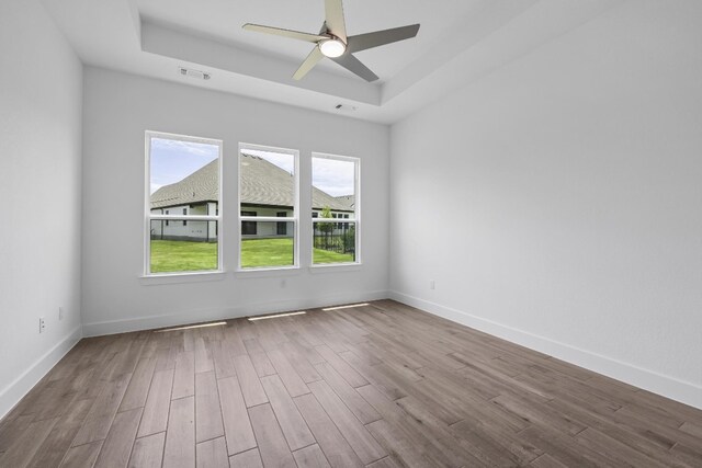 unfurnished room with hardwood / wood-style flooring, a raised ceiling, and ceiling fan