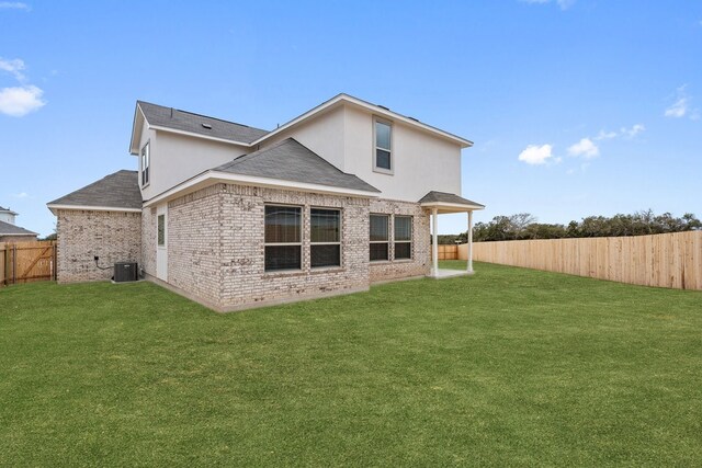 rear view of property featuring a lawn and central air condition unit