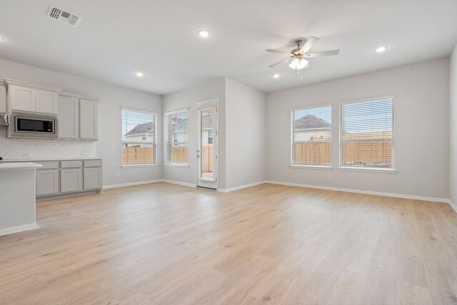 unfurnished living room with light hardwood / wood-style flooring, ceiling fan, and plenty of natural light