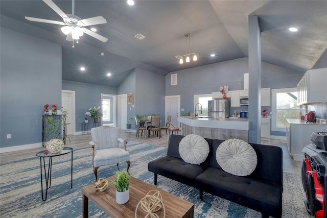 living room with sink, high vaulted ceiling, and ceiling fan with notable chandelier