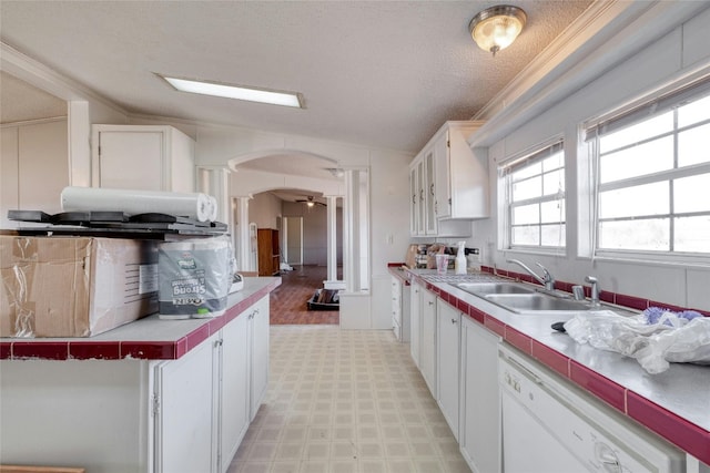 kitchen with white cabinetry, dishwasher, sink, light tile flooring, and vaulted ceiling