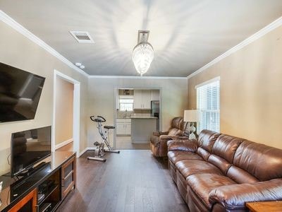 living room with an inviting chandelier, dark wood-type flooring, and ornamental molding