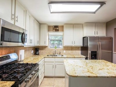 kitchen with light stone countertops, white cabinetry, sink, and stainless steel appliances