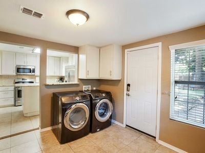 clothes washing area featuring cabinets, separate washer and dryer, and light tile patterned flooring