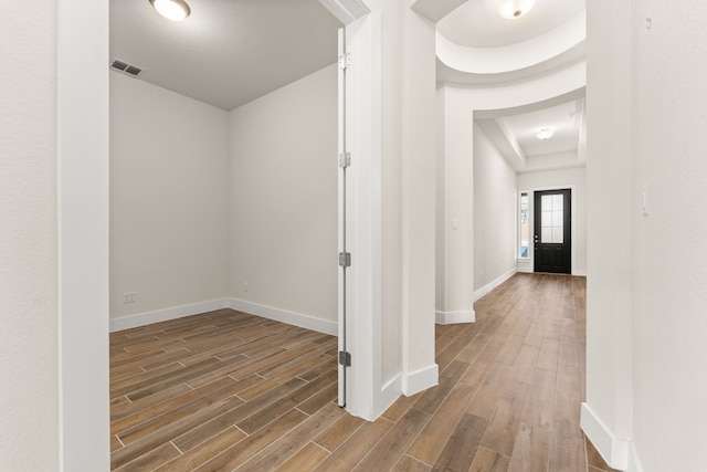 corridor featuring wood finish floors, visible vents, and baseboards