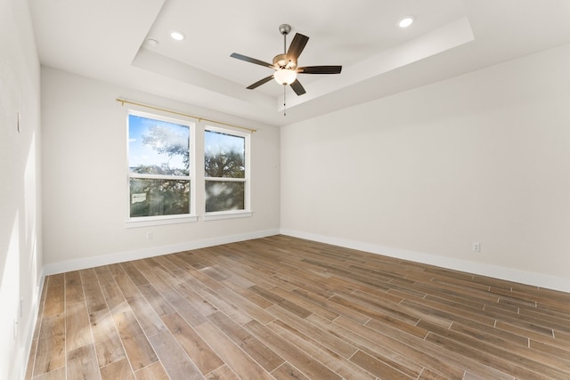 unfurnished room with hardwood / wood-style flooring, ceiling fan, and a raised ceiling