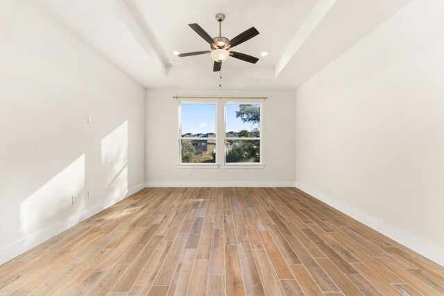 unfurnished room with recessed lighting, a raised ceiling, a ceiling fan, light wood-type flooring, and baseboards