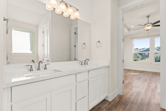 full bathroom with double vanity, wood finished floors, a sink, and baseboards