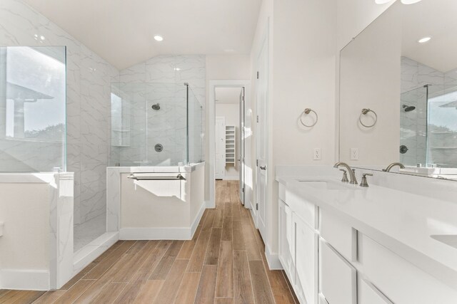 bathroom with hardwood / wood-style floors, vanity, a tile shower, and lofted ceiling