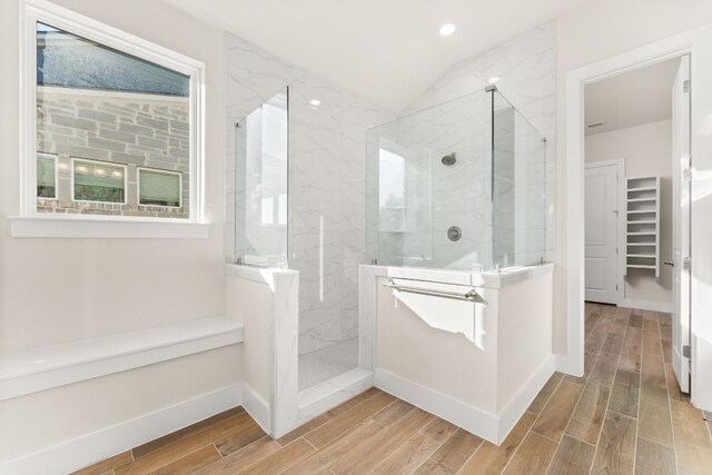 full bath featuring wood finish floors, a marble finish shower, and baseboards