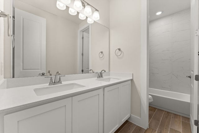 full bath featuring double vanity, toilet, a sink, and wood finish floors