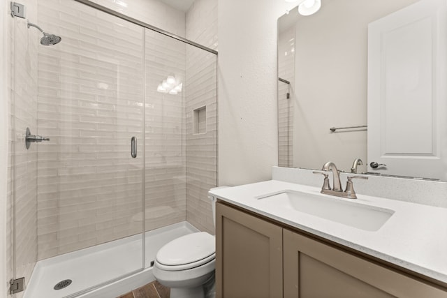 bathroom featuring vanity, a shower stall, and toilet