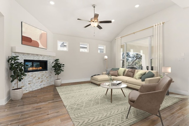 living room featuring lofted ceiling, wood tiled floor, baseboards, and ceiling fan