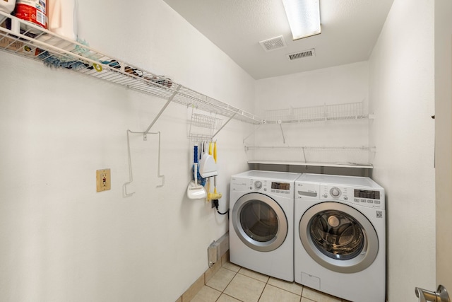 laundry room featuring washing machine and dryer and light tile patterned flooring