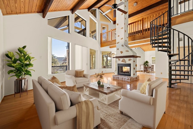 living room with ceiling fan, high vaulted ceiling, beamed ceiling, and a fireplace