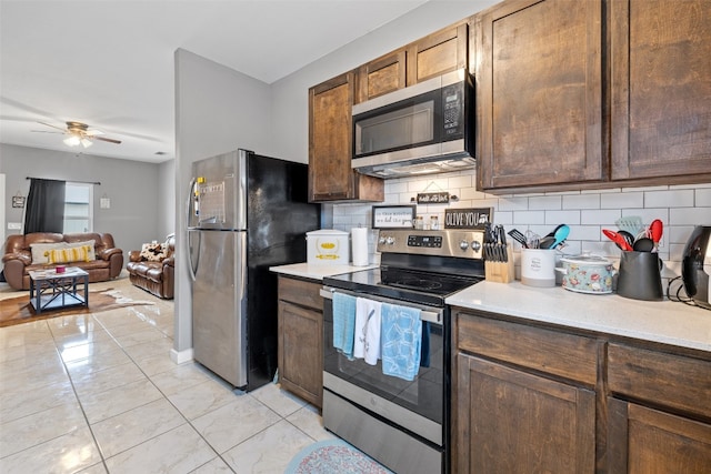 kitchen featuring ceiling fan, appliances with stainless steel finishes, light tile flooring, tasteful backsplash, and dark brown cabinetry