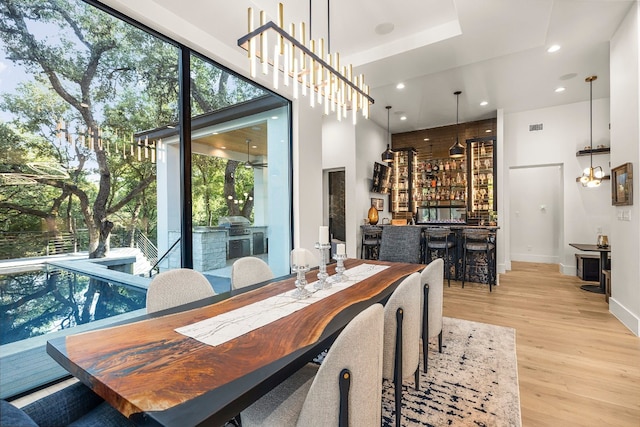 dining room with bar, a chandelier, and light wood-type flooring