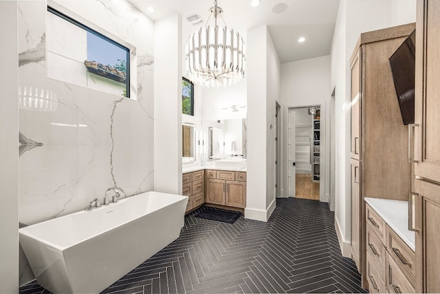 bathroom with a towering ceiling, a tub to relax in, parquet floors, vanity, and an inviting chandelier