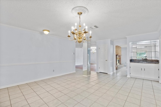 tiled empty room with crown molding, a fireplace, a textured ceiling, and an inviting chandelier