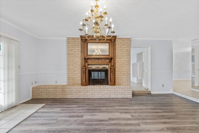 unfurnished living room featuring crown molding, hardwood / wood-style flooring, a fireplace, a textured ceiling, and a chandelier